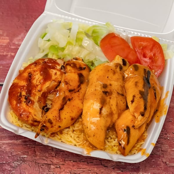 Firebird Piri Piri Grill's chicken with rice, lettuce, and tomato in a takeout container.