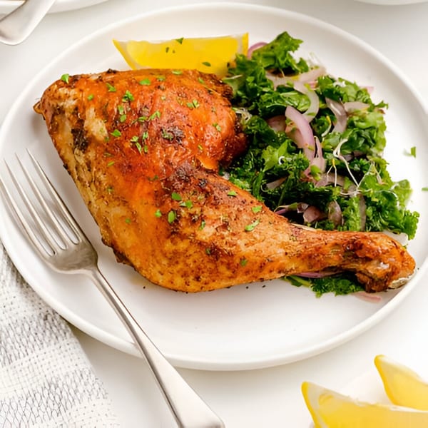 Firebird Piri Piri Grill's roasted chicken leg quarter with a side of kale salad and lemon.